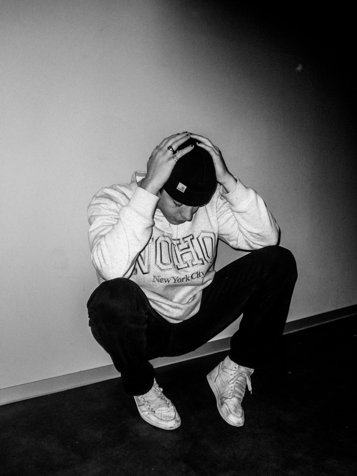 man in hoodie and pants sitting on floor