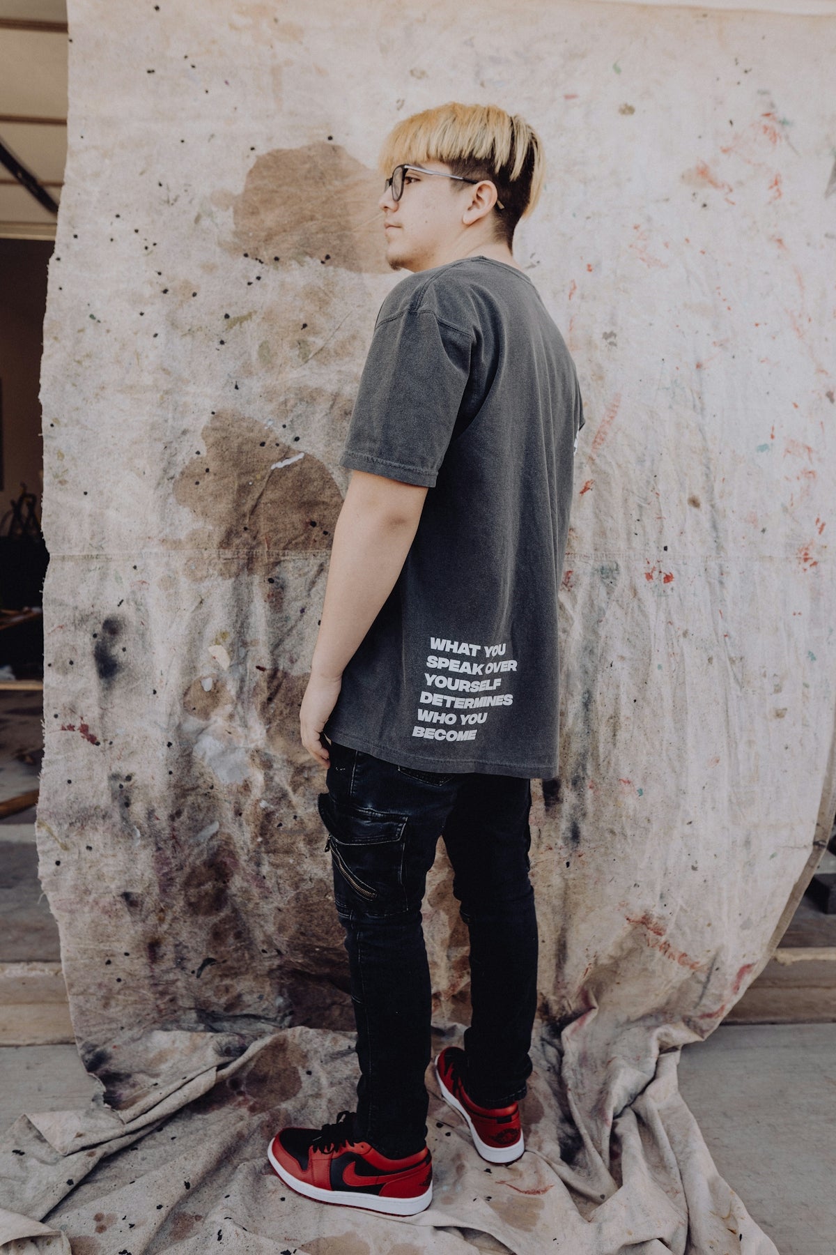 a young man standing in front of a large piece of art