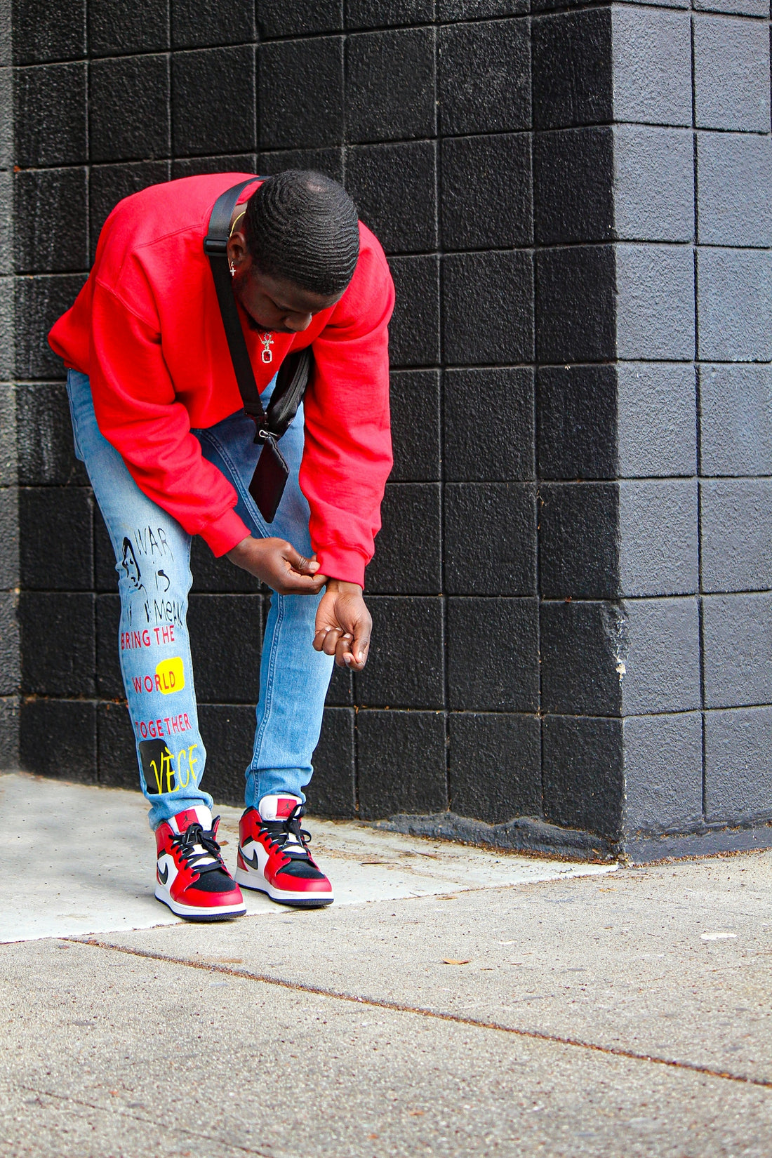 a man in a red jacket leaning against a wall