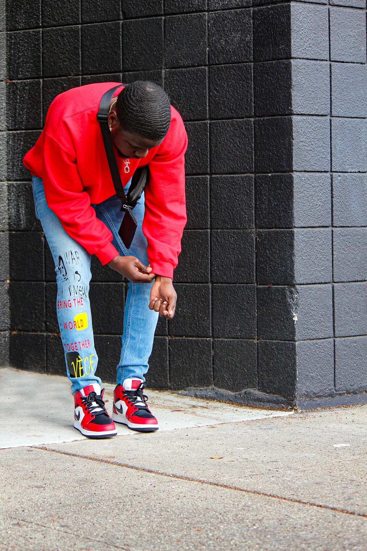 a man in a red jacket leaning against a wall