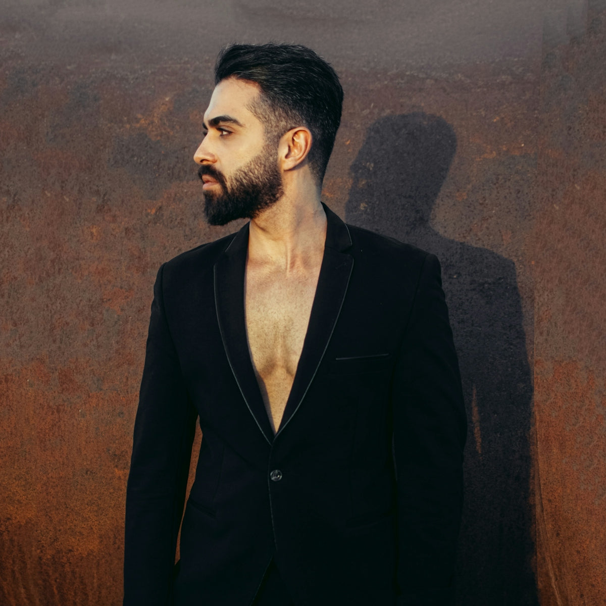 a man with a beard standing in front of a wall