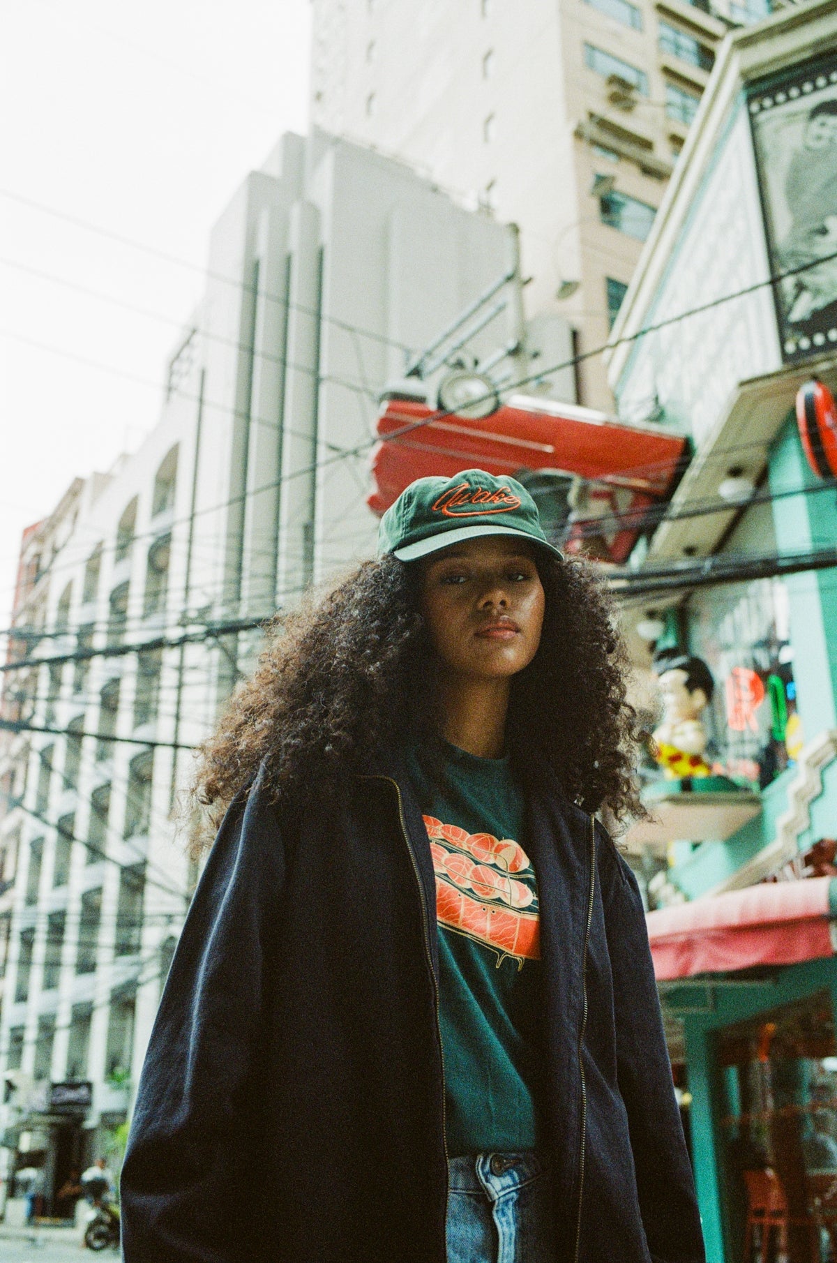 A woman standing on a city street with a skateboard on her head
