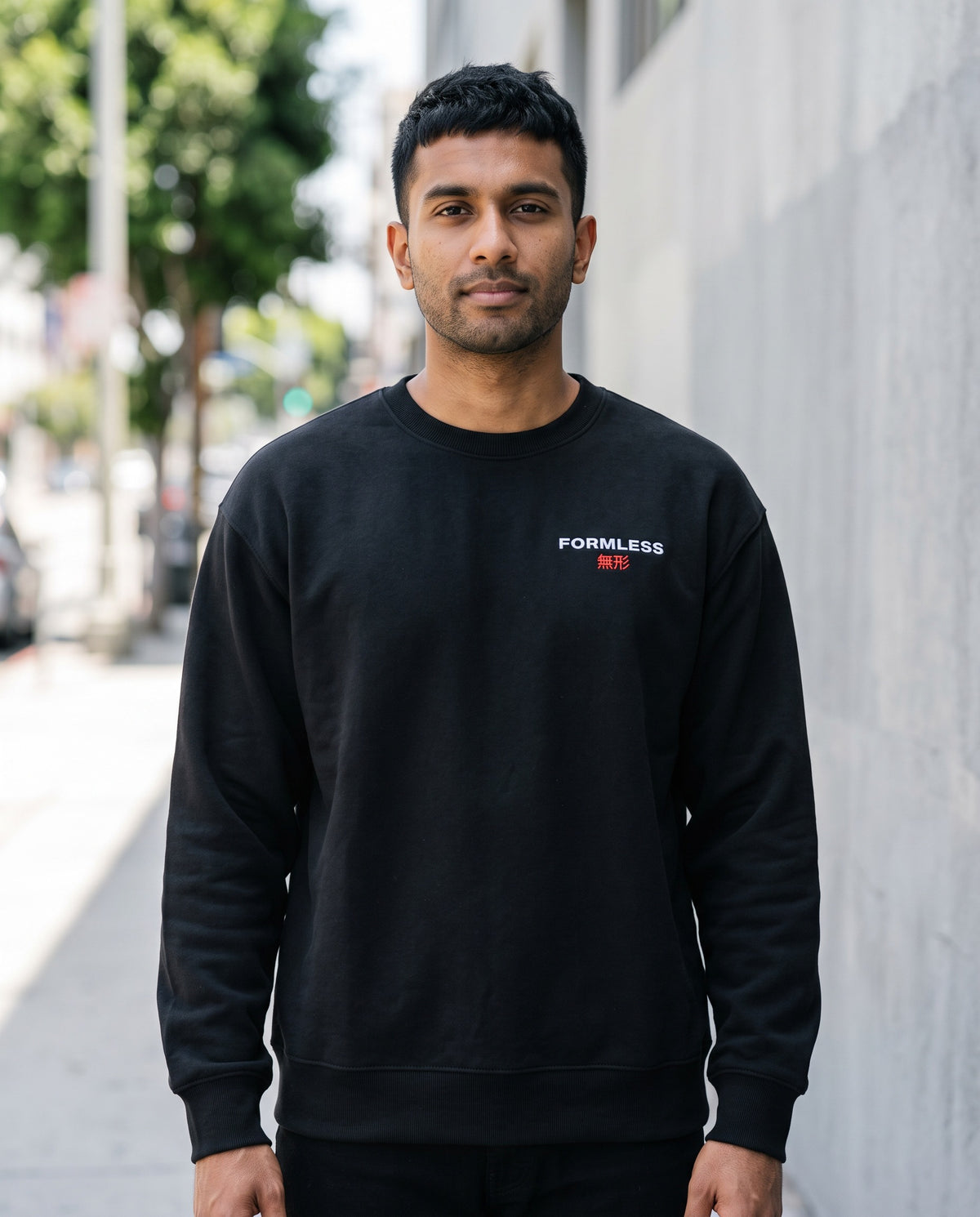 FORMLESS 無形 embroidered logo crewneck in black, front view, worn by a man