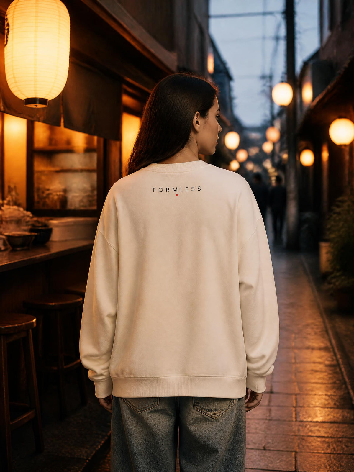 RAMEN GIRL 拉麺 boxy fleece sweatshirt in Apricot cream worn by a model in a Tokyo ramen alley at dusk, back view with small FORMLESS wordmark | Formless
